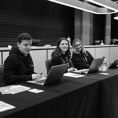 A group of people sitting at a table with laptopsDescription automatically generated