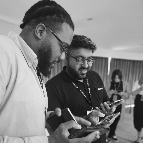 A group of men looking at their phonesDescription automatically generated