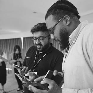 A group of men looking at their phonesDescription automatically generated